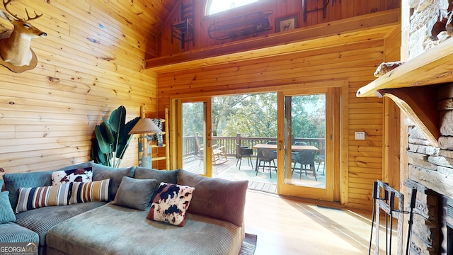 living room featuring high vaulted ceiling, wooden walls, and light hardwood / wood-style floors