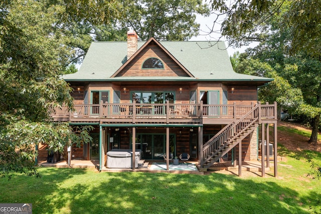 back of property featuring a wooden deck, a hot tub, a patio area, and a yard