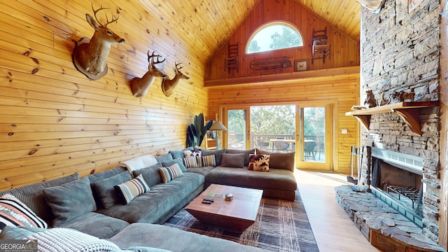 living room featuring wood ceiling, a stone fireplace, high vaulted ceiling, wooden walls, and wood-type flooring