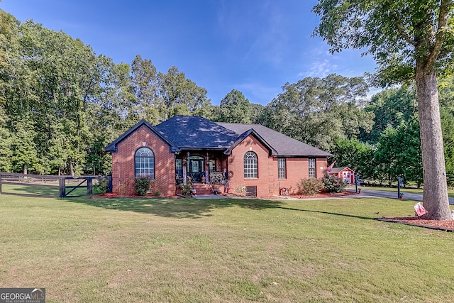 view of front of home featuring roof with shingles, a front yard, fence, and brick siding