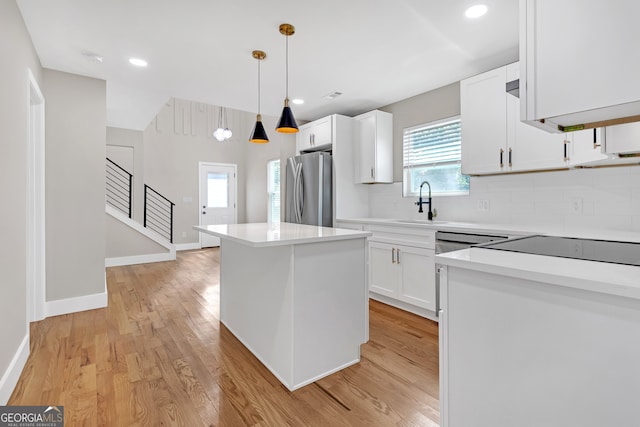 kitchen with plenty of natural light, a center island, stainless steel refrigerator, and pendant lighting