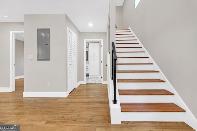 stairway with electric panel and hardwood / wood-style flooring