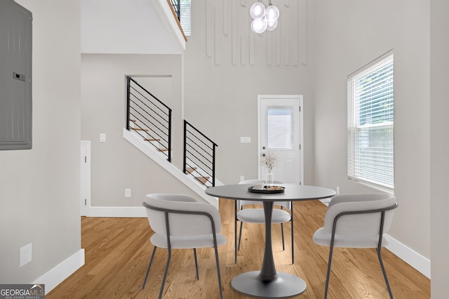 dining area featuring electric panel, a high ceiling, and light hardwood / wood-style floors