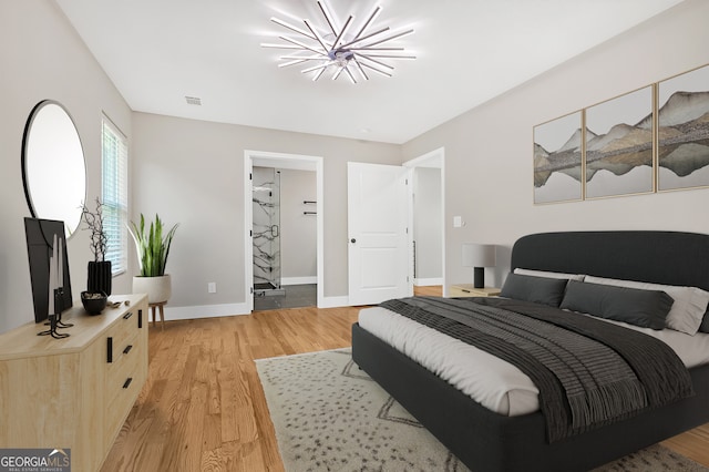 bedroom featuring a notable chandelier, a spacious closet, and light hardwood / wood-style floors