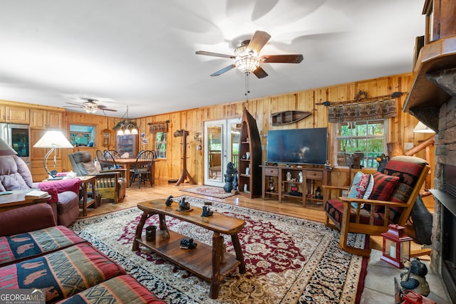 living room featuring ceiling fan, wooden walls, light hardwood / wood-style floors, and a fireplace