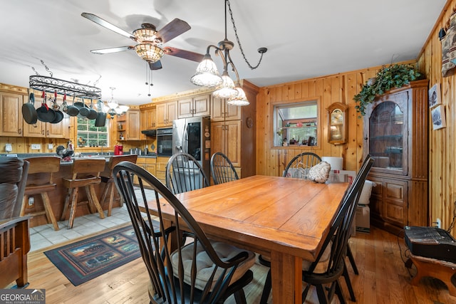 dining room featuring wood walls, light hardwood / wood-style flooring, and ceiling fan