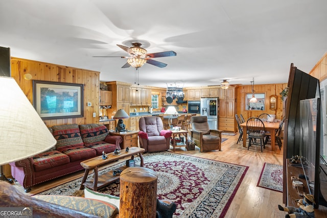 living room featuring wood walls, light hardwood / wood-style flooring, and ceiling fan