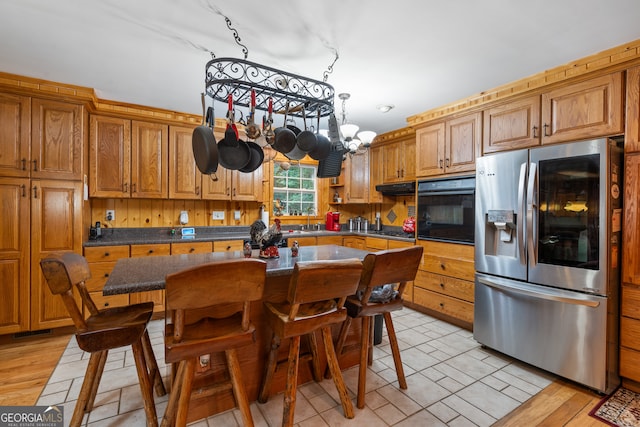 kitchen with light hardwood / wood-style flooring, oven, stainless steel refrigerator with ice dispenser, extractor fan, and a notable chandelier