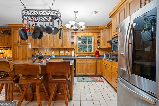 kitchen featuring decorative backsplash, a chandelier, light tile patterned floors, sink, and stainless steel appliances