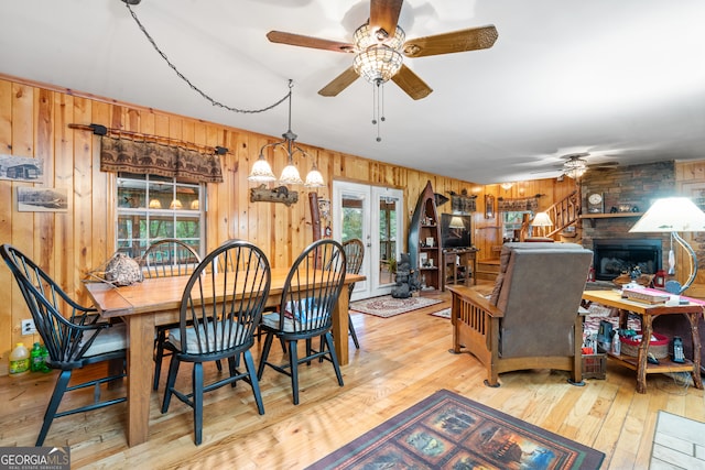 dining room with wood walls, ceiling fan, light hardwood / wood-style floors, and french doors