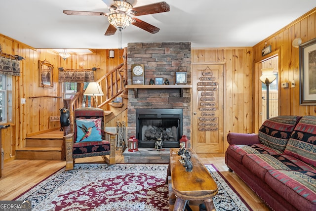 living room with ceiling fan, a fireplace, wood walls, and wood-type flooring