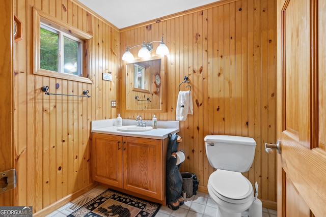 bathroom featuring wood walls, vanity, crown molding, tile patterned floors, and toilet