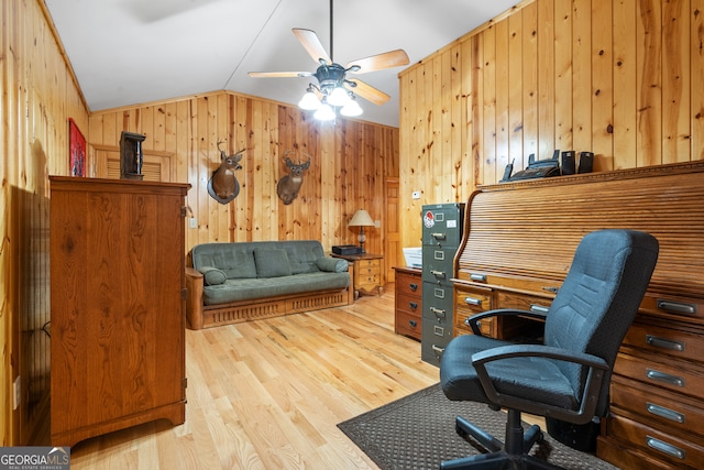 office space featuring ceiling fan, vaulted ceiling, light hardwood / wood-style flooring, and wood walls