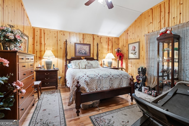 bedroom with ceiling fan, wooden walls, vaulted ceiling, and hardwood / wood-style floors