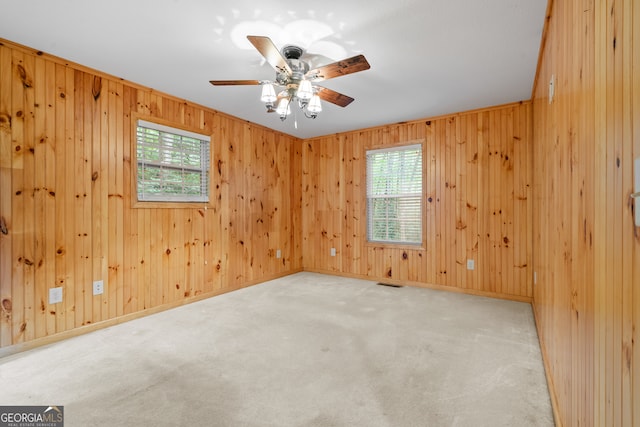 carpeted empty room featuring ceiling fan and wooden walls