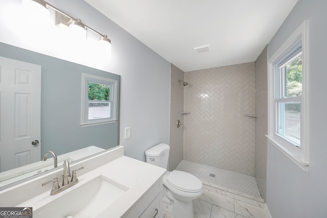 bathroom with vanity, toilet, and tiled shower