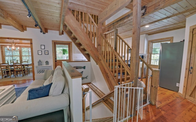 staircase with a notable chandelier, track lighting, hardwood / wood-style floors, and wood ceiling