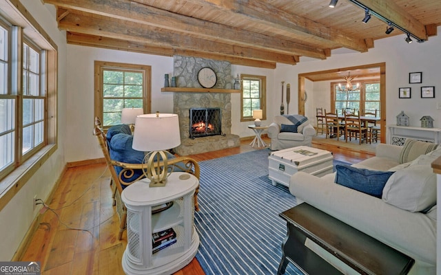 living room with light hardwood / wood-style floors, beam ceiling, a fireplace, and a healthy amount of sunlight