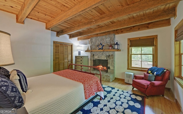 bedroom with beam ceiling, light hardwood / wood-style floors, wooden ceiling, and a stone fireplace