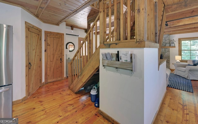 kitchen featuring wood ceiling, light hardwood / wood-style flooring, beamed ceiling, and stainless steel refrigerator