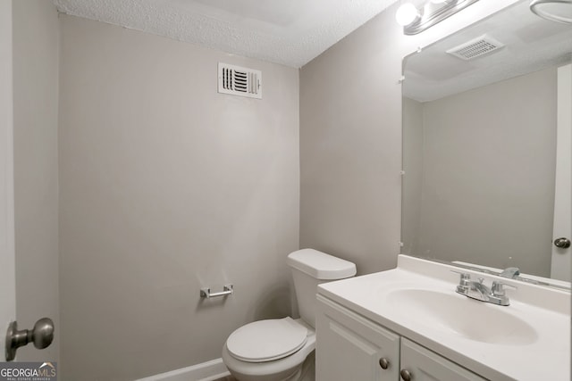 bathroom with a textured ceiling, toilet, and vanity