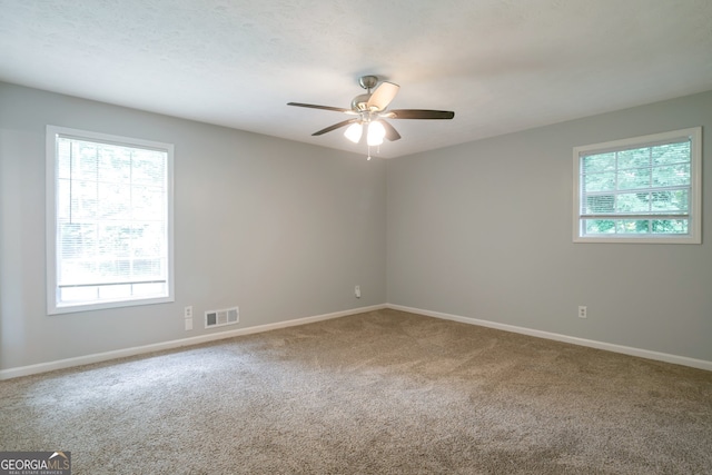 spare room featuring a wealth of natural light, carpet floors, and ceiling fan