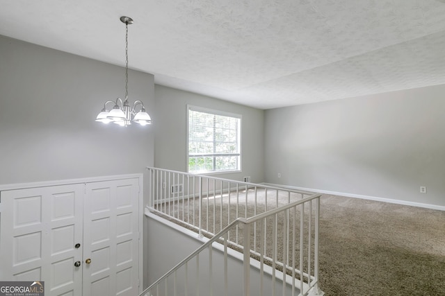 hallway featuring carpet, a textured ceiling, and a chandelier