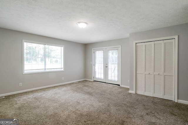 unfurnished bedroom featuring carpet flooring, a textured ceiling, and multiple windows