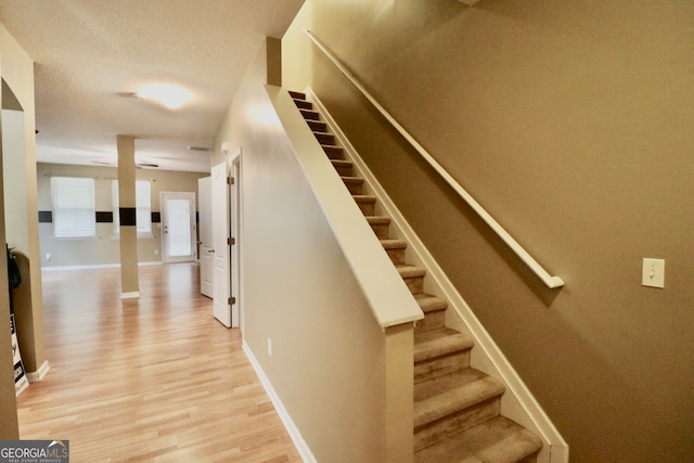 stairway featuring a textured ceiling and hardwood / wood-style floors