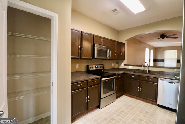 kitchen featuring stainless steel appliances, dark brown cabinets, sink, light tile patterned floors, and ceiling fan