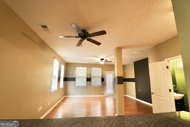 interior space featuring hardwood / wood-style floors, sink, ceiling fan, and a textured ceiling