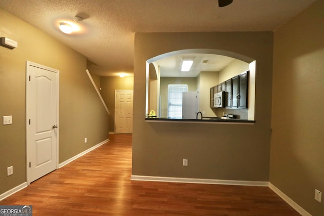 unfurnished living room featuring sink, a textured ceiling, and hardwood / wood-style floors