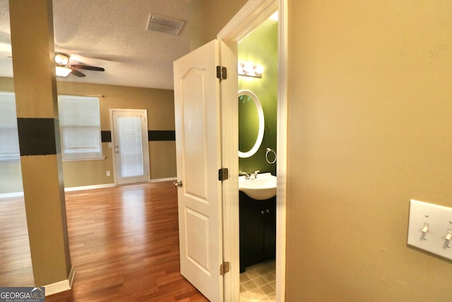 hallway featuring sink, a textured ceiling, and wood-type flooring