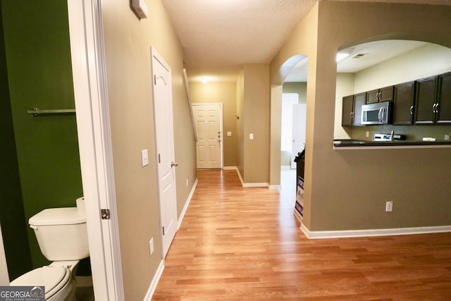 hall featuring a textured ceiling and light hardwood / wood-style flooring