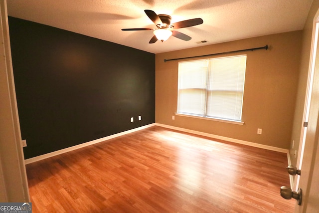 spare room with a textured ceiling, ceiling fan, and hardwood / wood-style floors