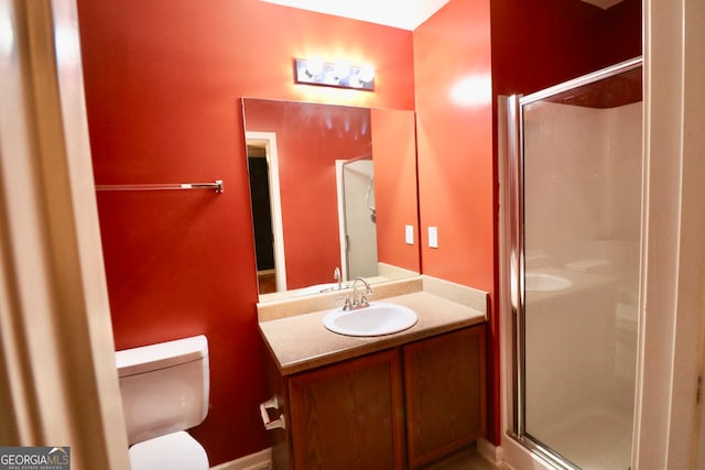 bathroom featuring a shower with door, vanity, and toilet