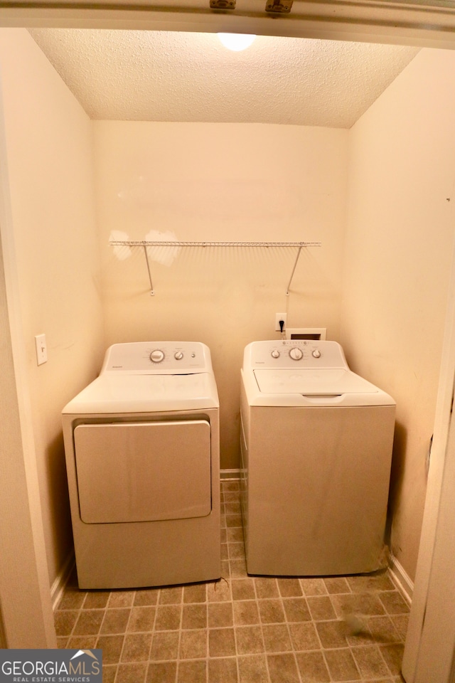 laundry area with tile patterned flooring, washing machine and dryer, and a textured ceiling