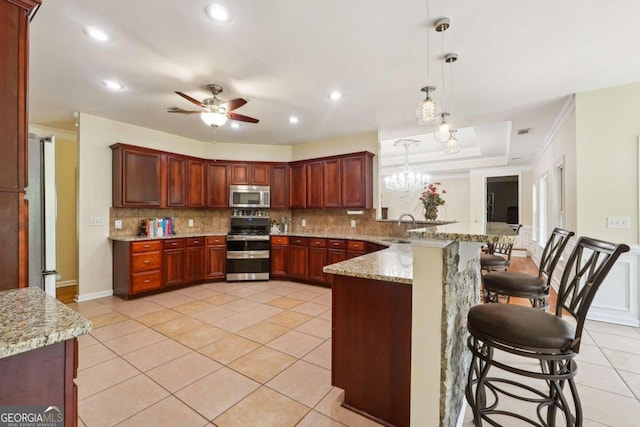 kitchen featuring pendant lighting, appliances with stainless steel finishes, sink, kitchen peninsula, and a breakfast bar area