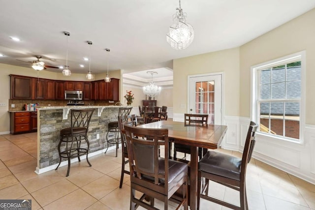 tiled dining space with ceiling fan with notable chandelier