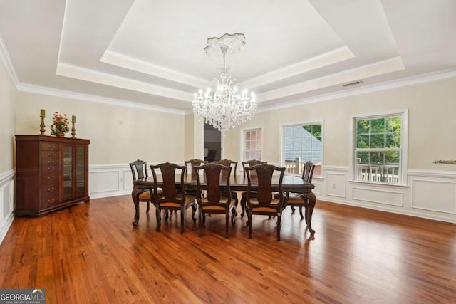 dining space with a tray ceiling, dark hardwood / wood-style flooring, crown molding, and a chandelier