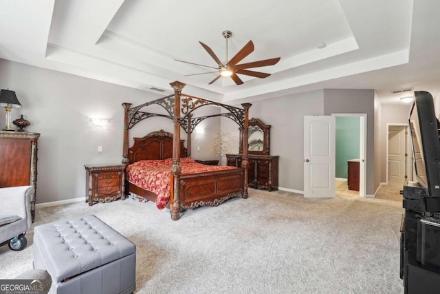 bedroom with ceiling fan, a tray ceiling, and light carpet