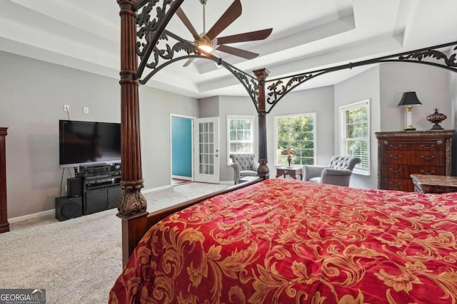 carpeted bedroom with ceiling fan and a raised ceiling