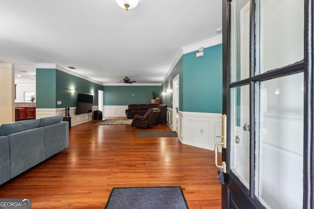 living room with hardwood / wood-style flooring, ceiling fan, and ornamental molding