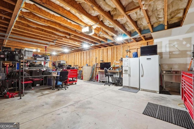 basement featuring sink, a workshop area, white refrigerator with ice dispenser, and white fridge