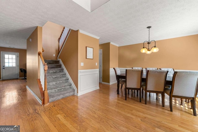 unfurnished dining area with a textured ceiling, a chandelier, and light wood-type flooring