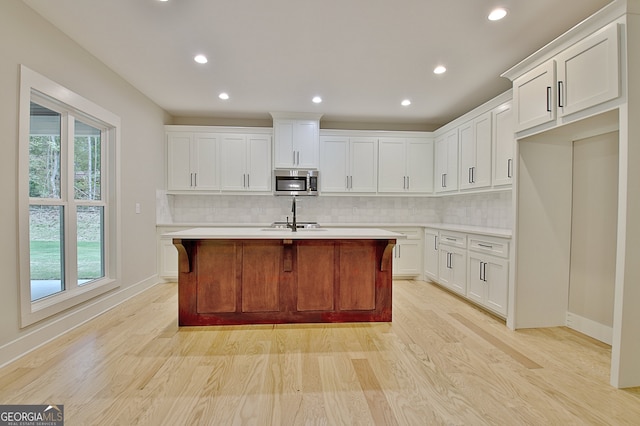 kitchen with white cabinets, a center island with sink, and plenty of natural light