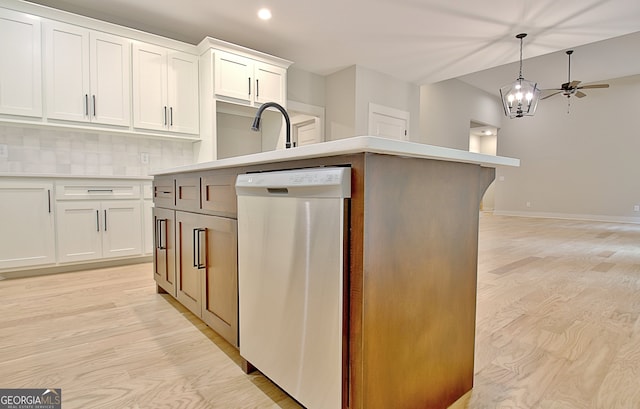 kitchen with a kitchen island with sink, backsplash, white cabinetry, and dishwasher