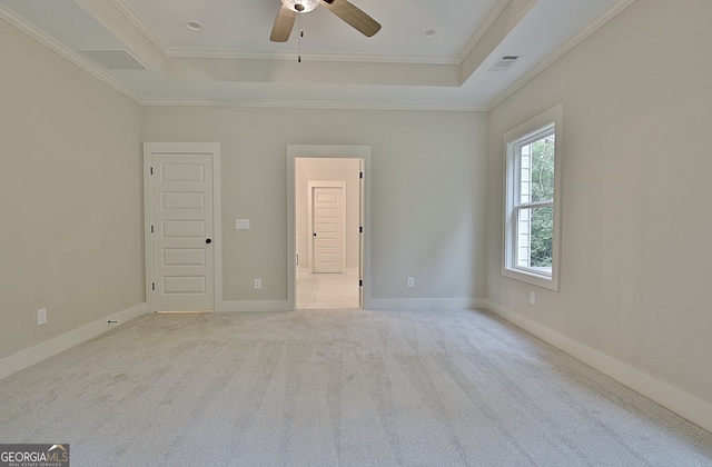 interior space featuring ceiling fan, a tray ceiling, light carpet, and ornamental molding