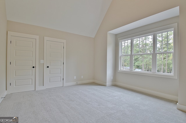 unfurnished bedroom featuring light colored carpet, lofted ceiling, and multiple windows