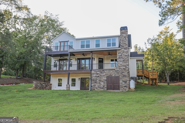 back of property featuring a lawn, a chimney, a balcony, and a ceiling fan